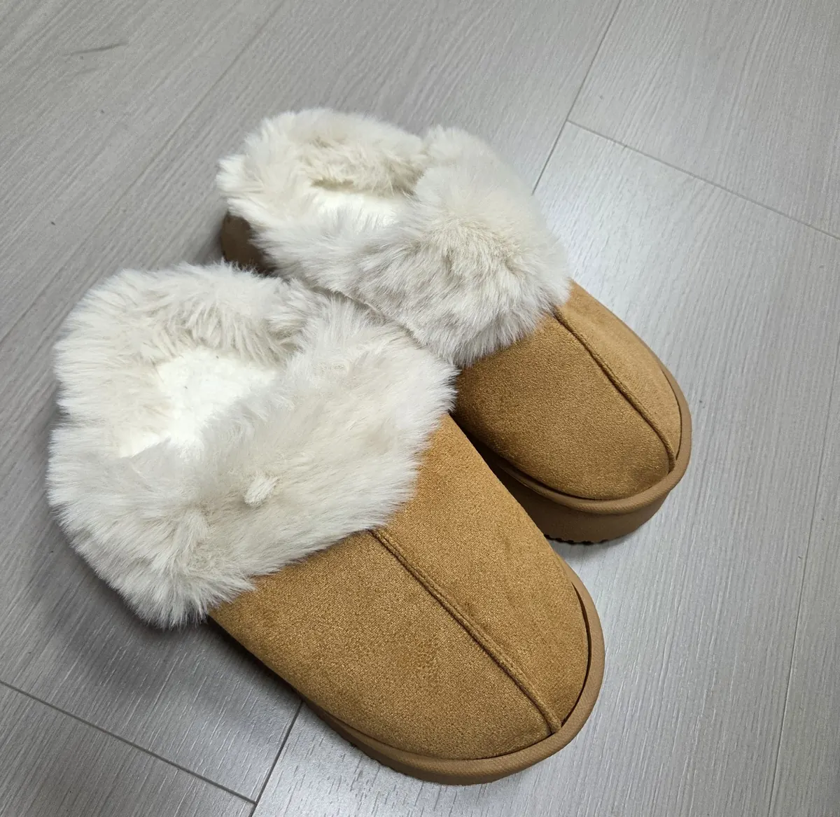 A pair of fur-lined suede slippers photographed from above, showing the moulded outsole edge