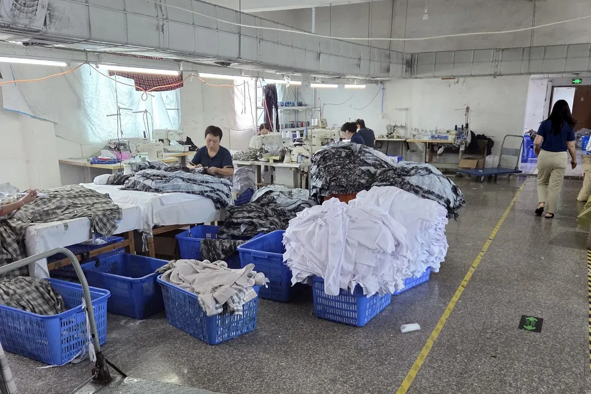 Bundled panels in bins beside sewing machines on a working production floor in China