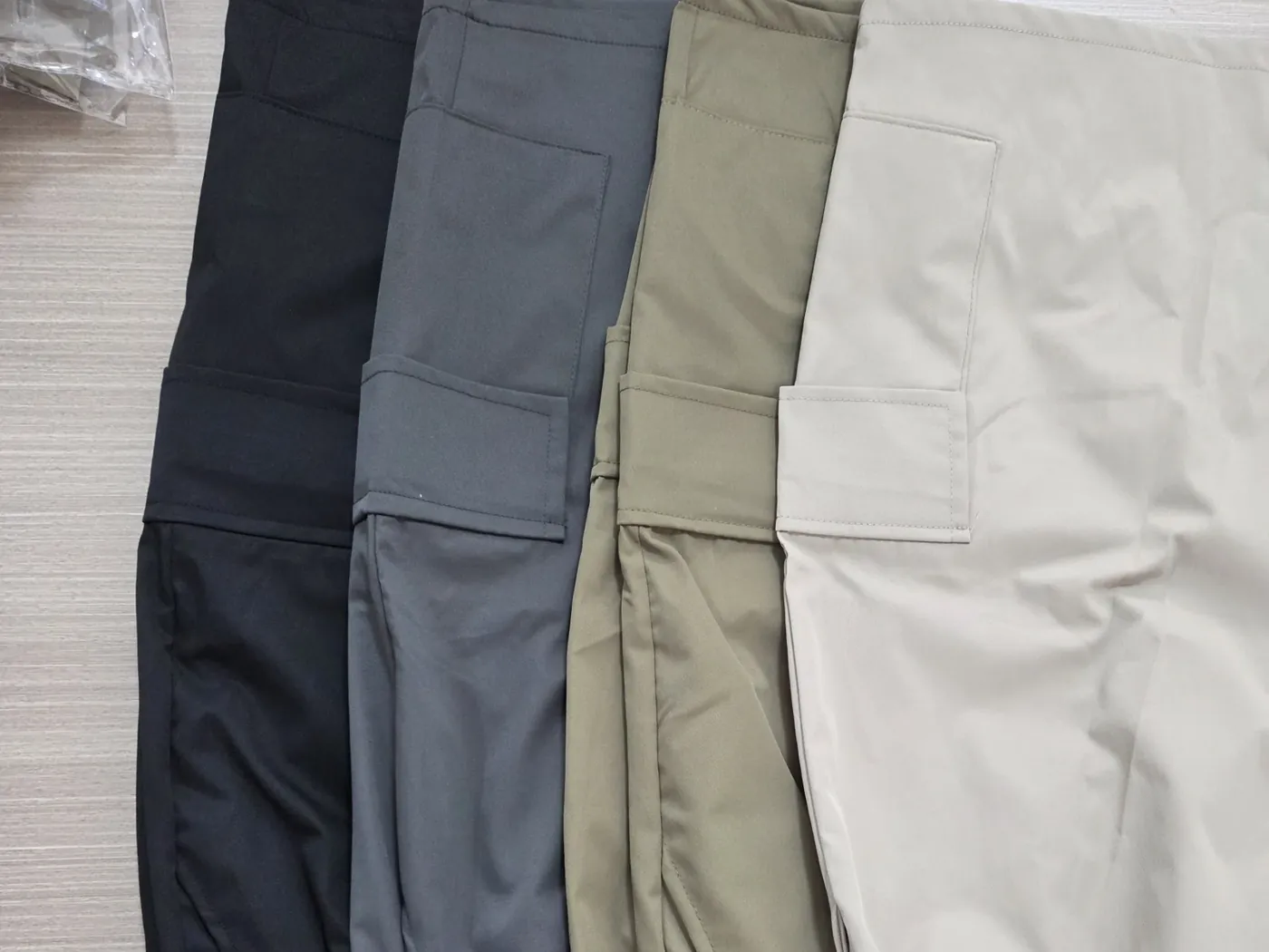 Four colourways of finished cargo trousers laid side by side for colour and spec check