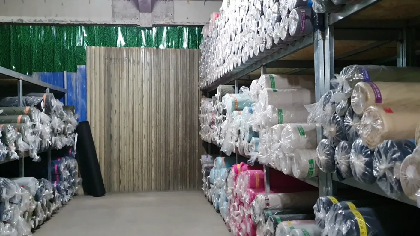Racks of fabric rolls stocked in the factory's material warehouse