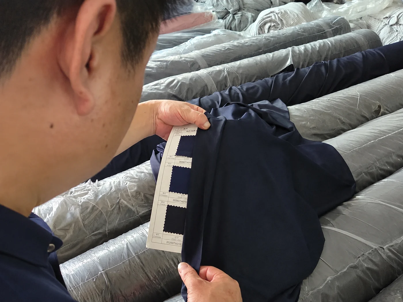 Fabric held against the approved colour card at the roll racks before cutting